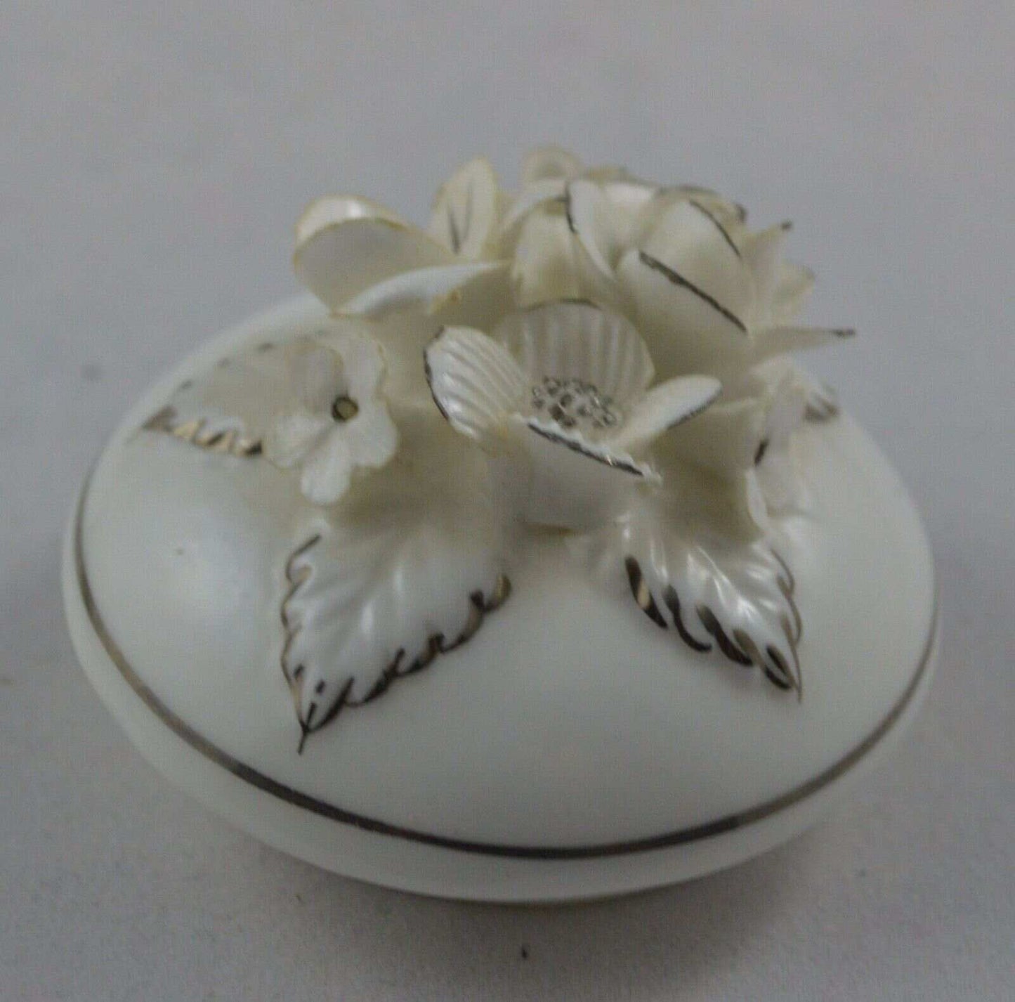 Small white flowers edged in gold gilding adorn the lid.